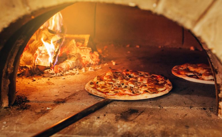 "Pizza artisanale en train de cuire dans un four à bois grand mère traditionnel. Saveur authentique garantie par notre food truck spécialisé en pizzas au feu de bois."